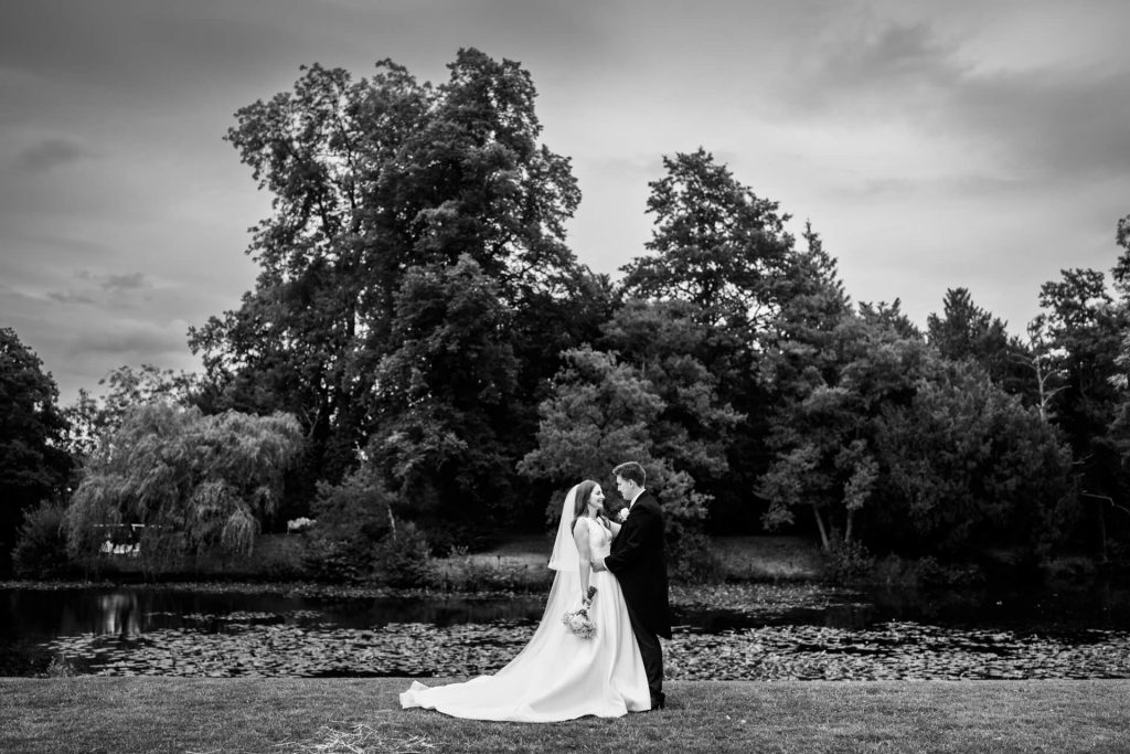 the wedding couple standing on the banks of the river at Thicket Priory