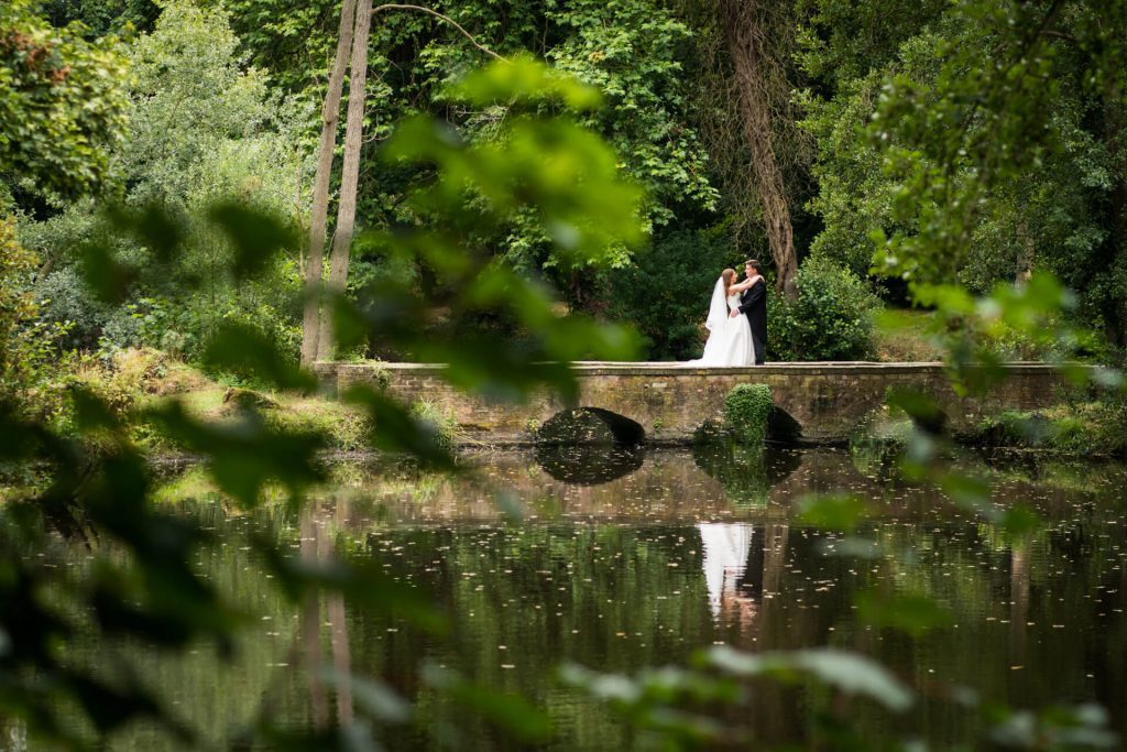 wedding couple cuddling on a bridge at Thicket Priory