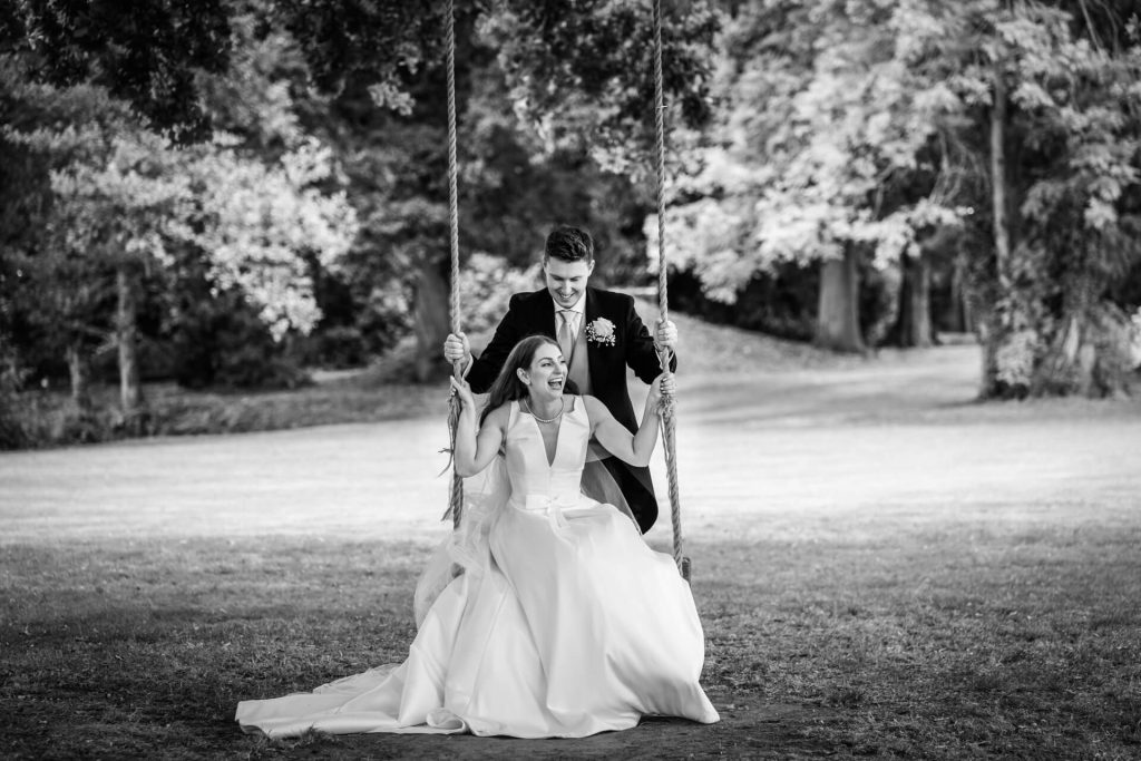 groom pushing the bride on a swing at Thicket Priory