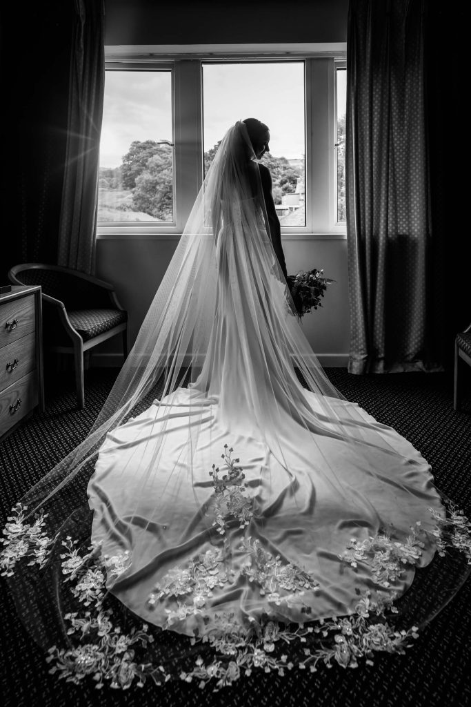 portrait of the bride next to a window showing the back of her dress