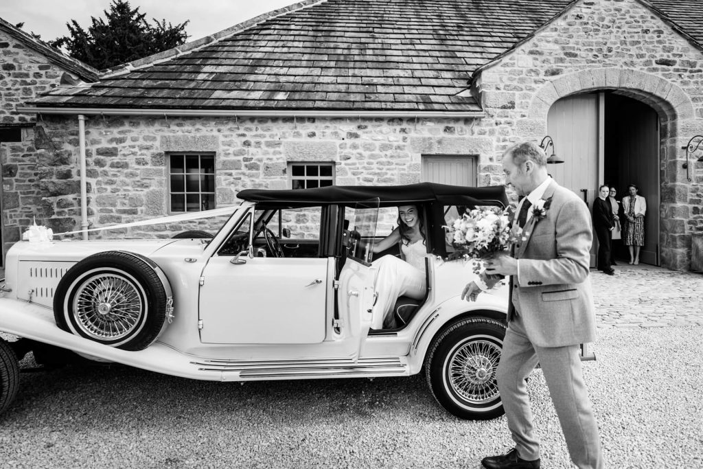 bride is about to leave the wedding car at Tithe Barn