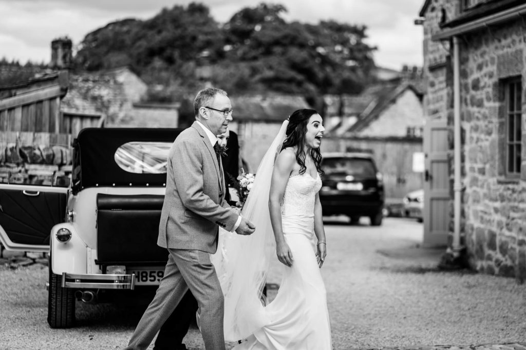 bride smiles with delight as she walks towards the wedding barn