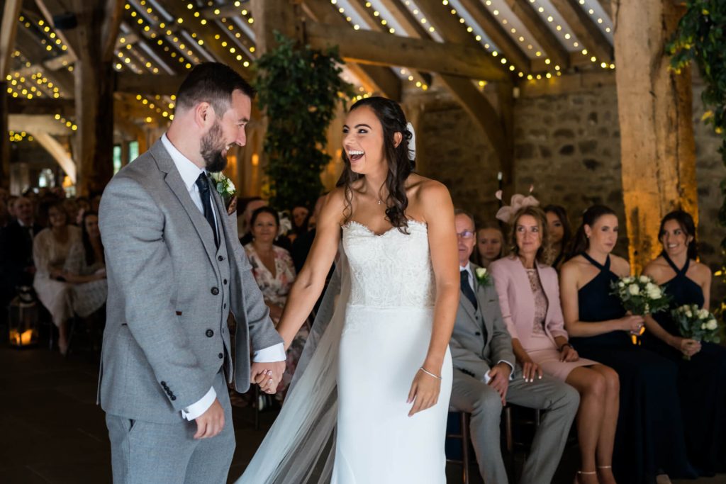 bride and groom laugh as they see each other at the top of the aisle