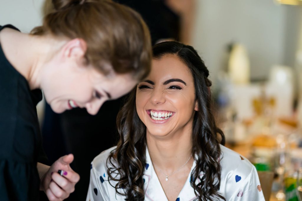 bride laughing with the make up artist