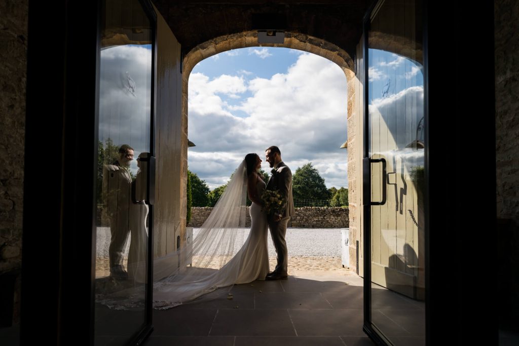 portrait of the wedding couple under the arch door at The Tithe Barn