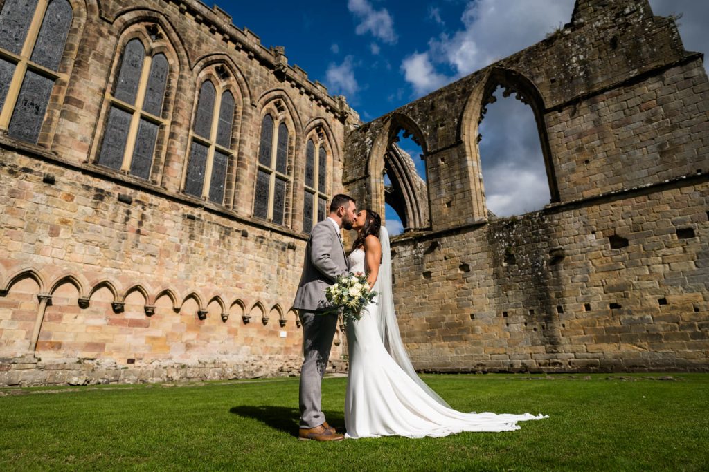 bride and groom kiss inside the Bolton Abbey ruins