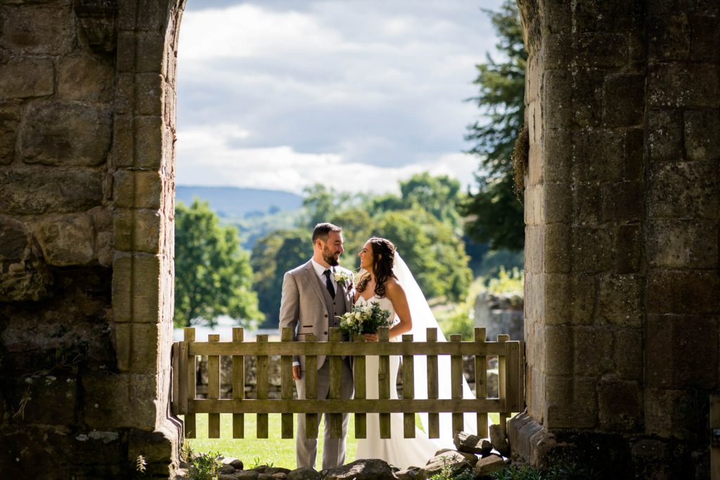 bride and groom smile at each other in the grounds of Bolton Abbey