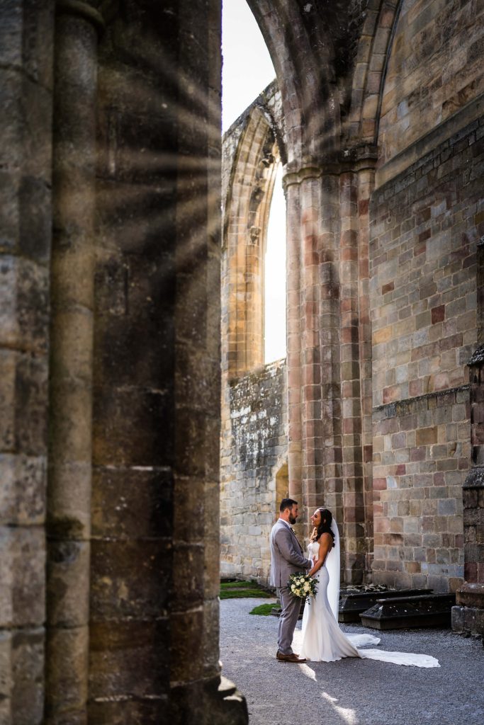 wedding couple standing under an archway at Bolton Abbey