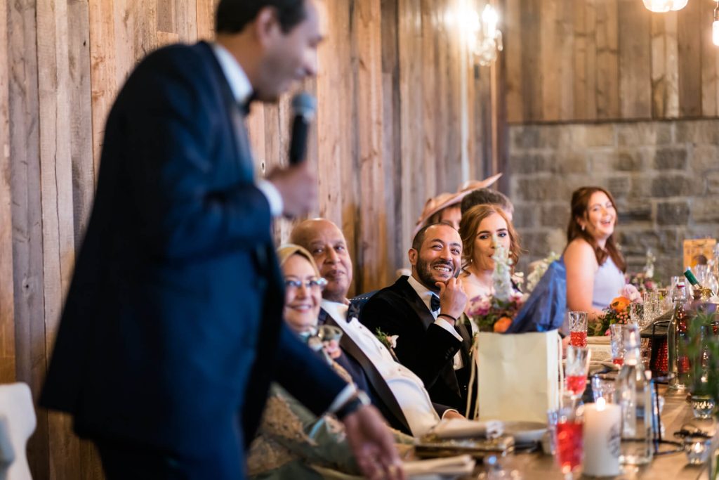 groom laughing at the best man as he gives his speech