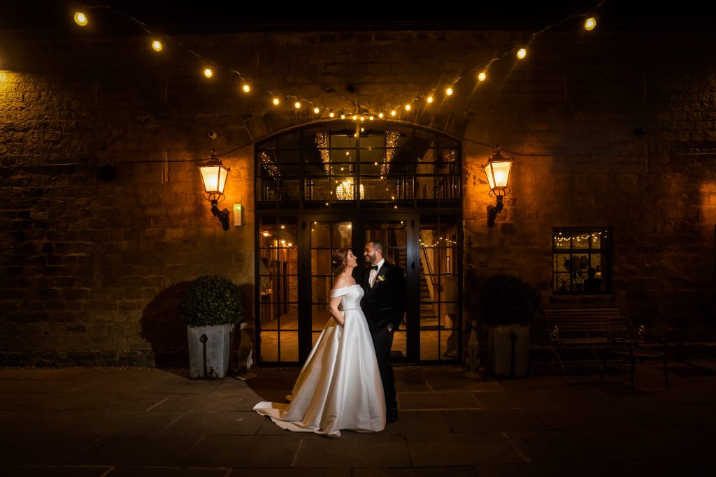 bride and groom portrait under fairy lights outside Wharfedale Grange
