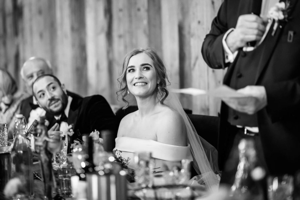 bride smiling up at her father as he makes his speech