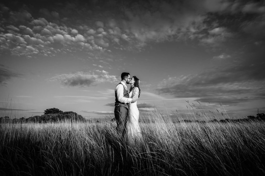 wedding couple kissing in a field at Woodstock wedding barn