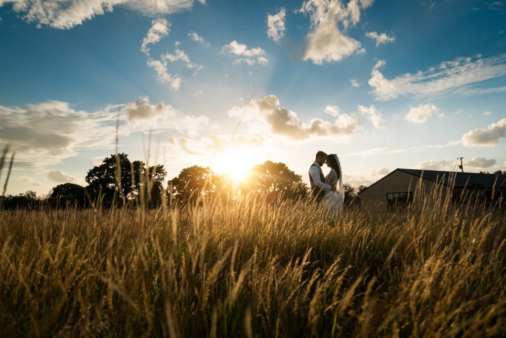 wedding couple hugging in a field at sunset at Woodstock weddings and events