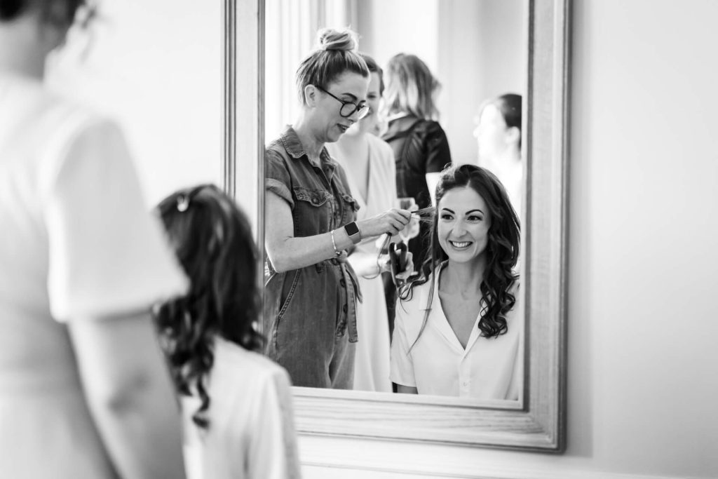 bride looking in a mirror and having her hair done