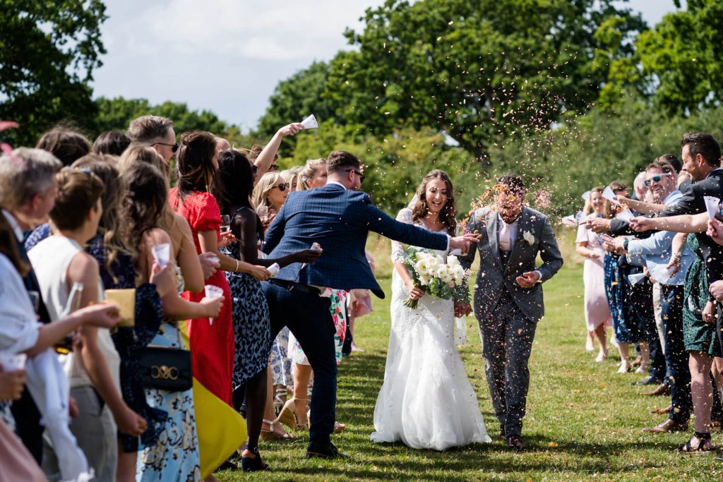 wedding guests shower the couple with confetti at Woodstock wedding barn