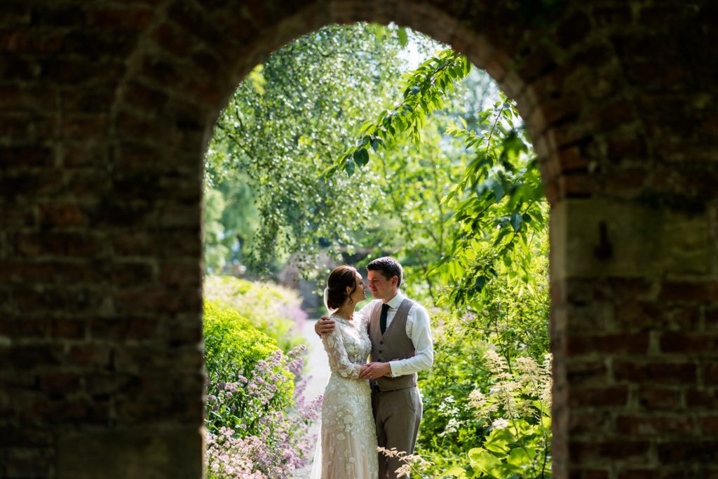 bride and groom embracing under an archway in the Middleton Lodge gardens