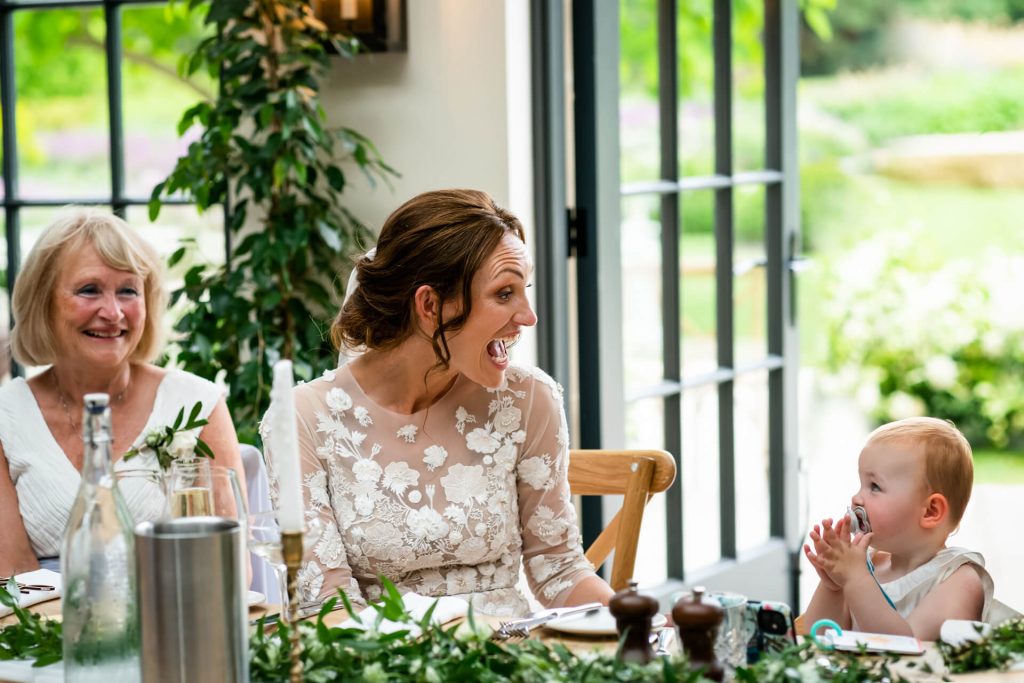 bride laughing at her baby girl as she claps during the speeches