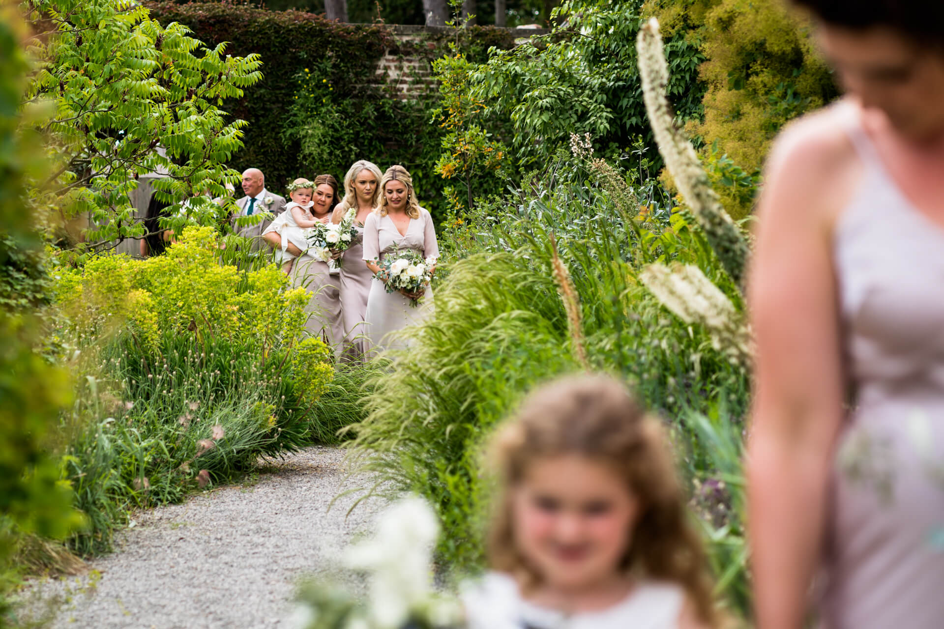 bridesmaids walking down a path towards the wedding ceremony