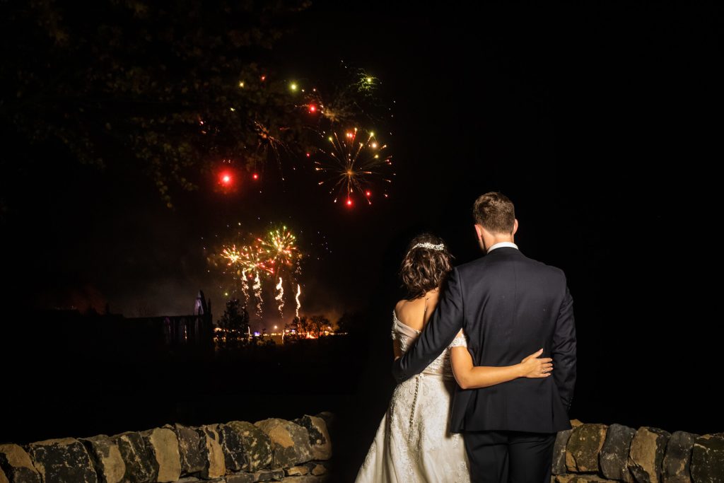 a couple watching fireworks over Bolton Abbey Estate, from tithe Barn