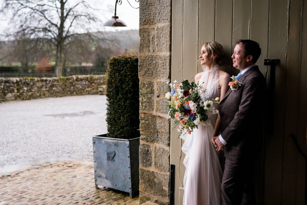 bride and groom holding hands in the doorway of Tithe Barn