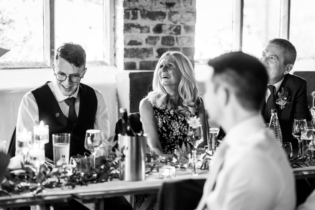 family of the groom laughing during his wedding speech