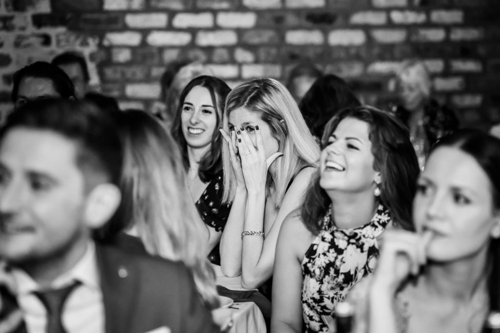 wedding guest covering her face whilst laughing