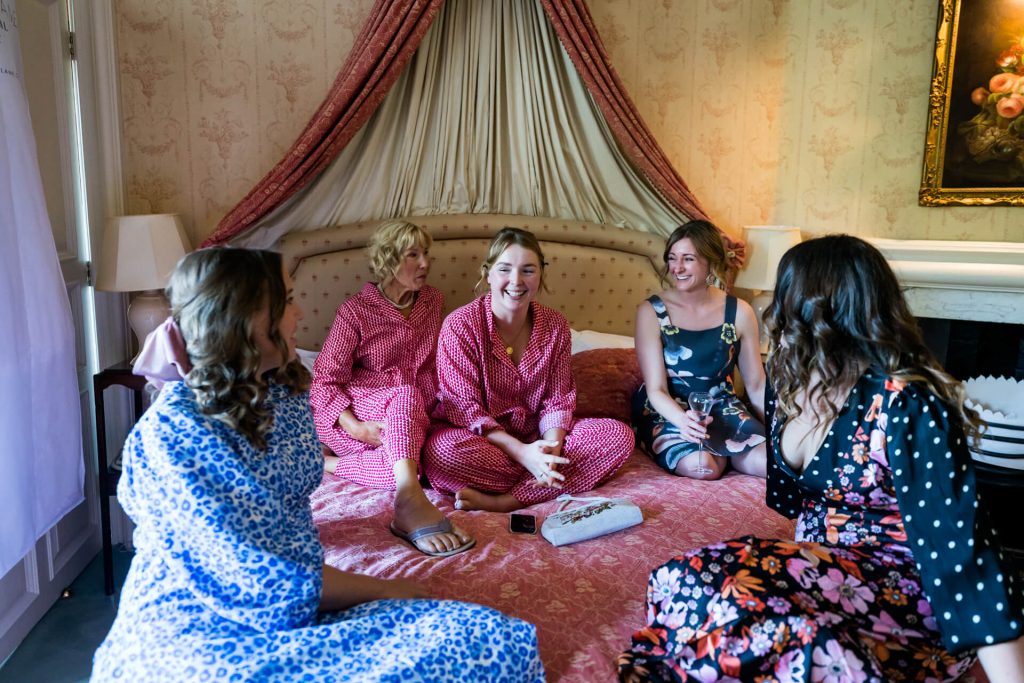 bridesmaids sitting on a bed together and laughing