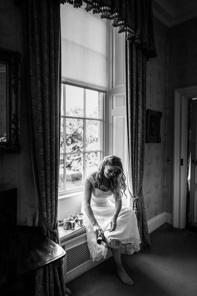bride sitting on a windowsill and putting on her shoes