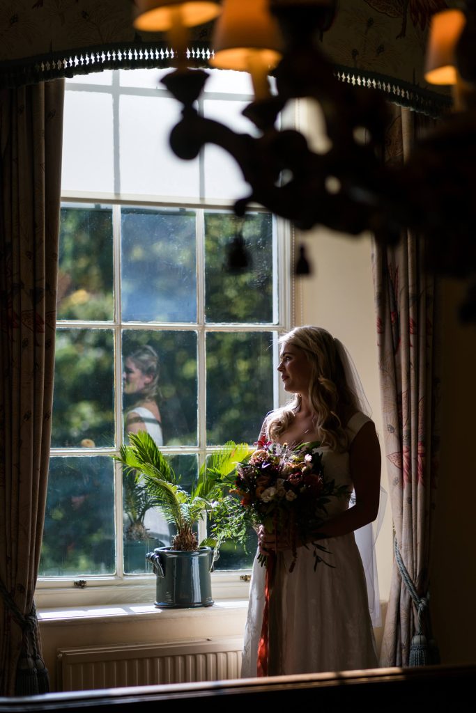 bride standing by a window holding her bouquet