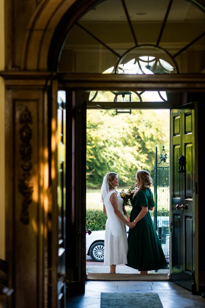 bride and her sister holding hands in a doorway at Middlethorpe Hall
