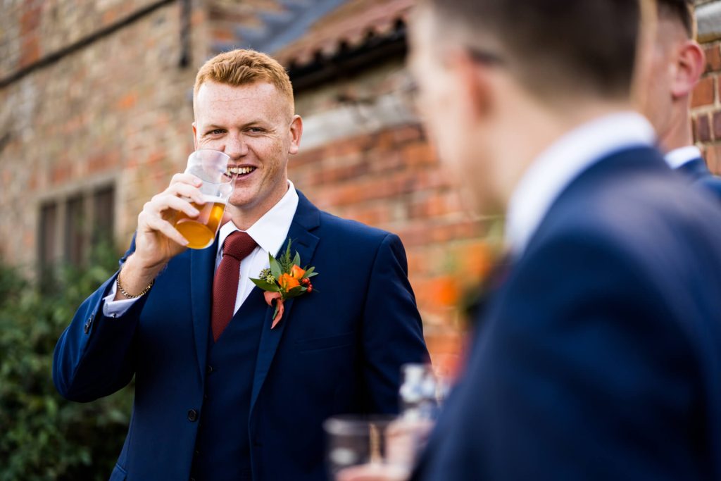 groomsman drinking his beer and laughing