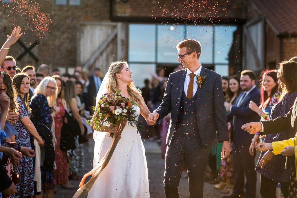 bride and groom are showered with confetti at Woolas Barn