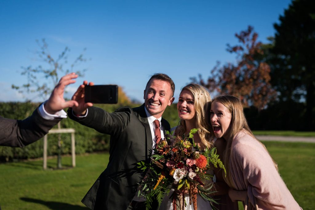 wedding guests smile as they take a selfie