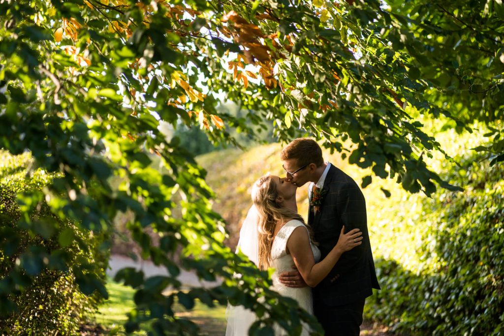 wedding couple kissing under a tree at Woolas Barn