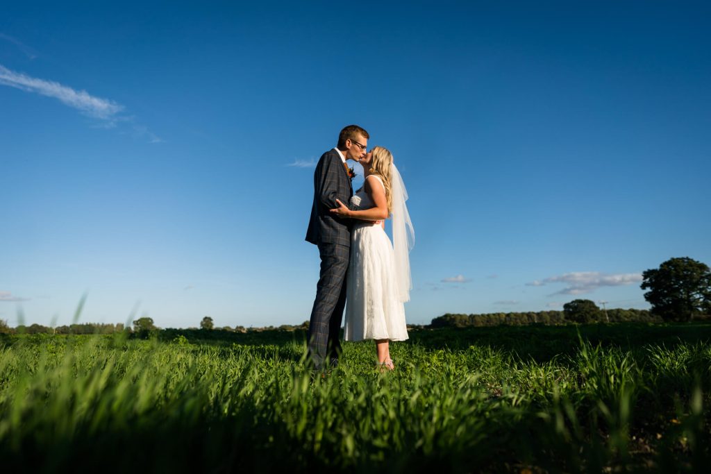 bride and groom kissing in a field