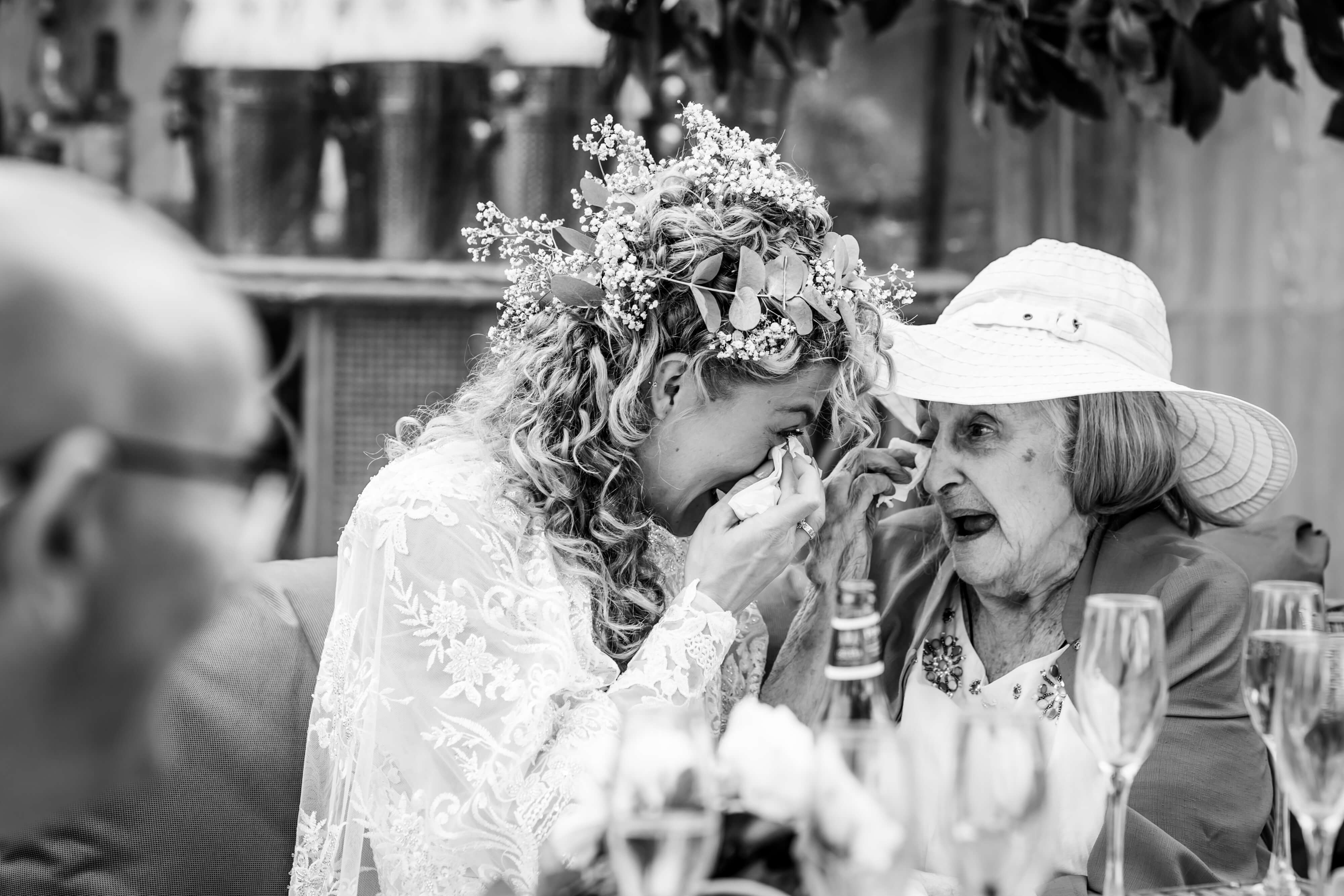 Bride in floral headpiece emotionally conversing with elderly guest