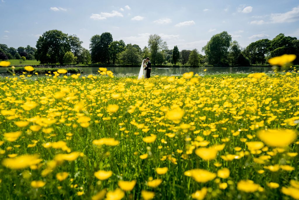 Couple embracing in yellow flower field by lake