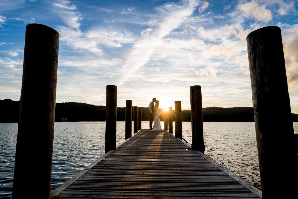 Couple embracing on sunset-lit pier by lake at the towhead estate