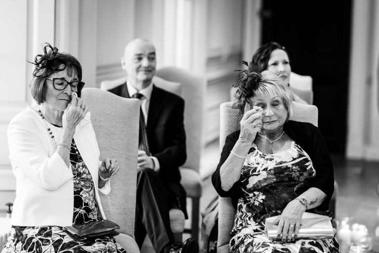 Guests emotional at wedding ceremony in black and white.