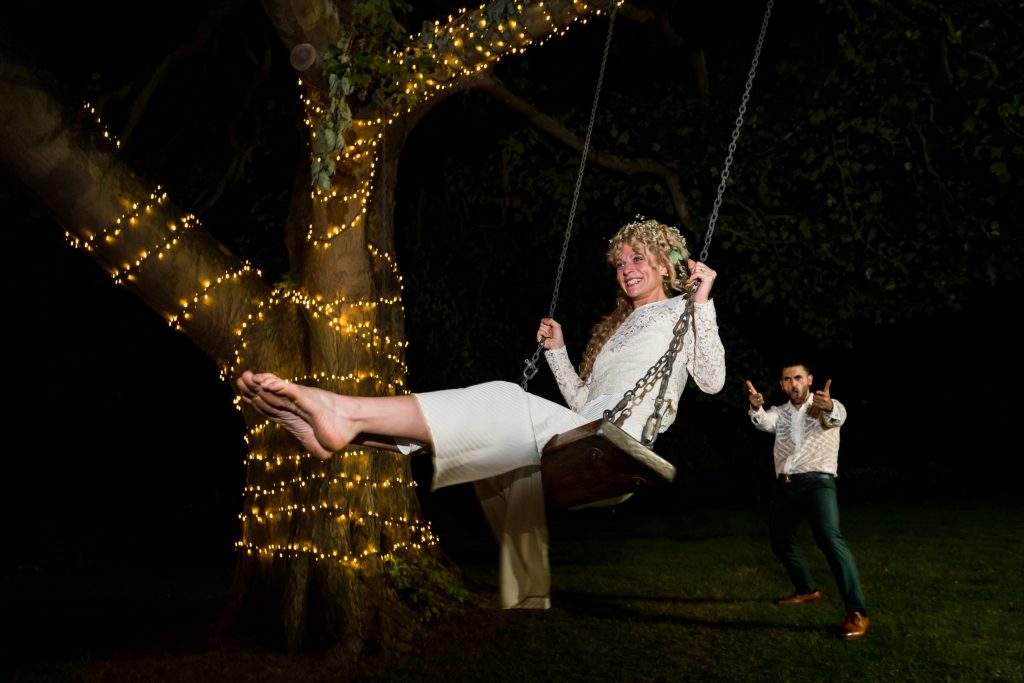 Groom pushing the bride on a swing at night