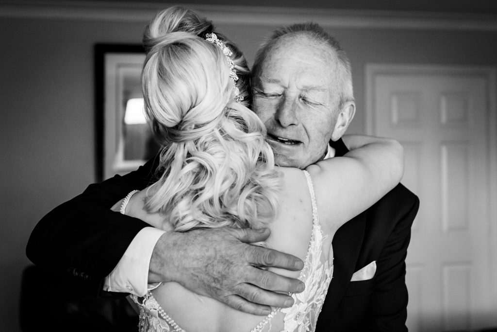 Bride hugging her father, emotional wedding moment.