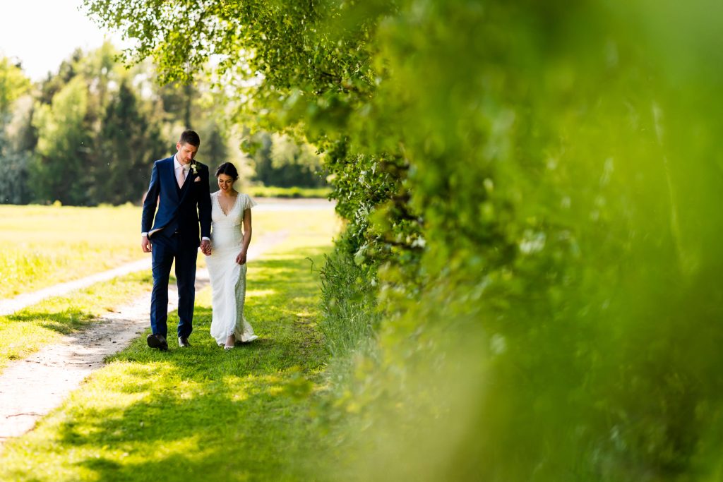 Bride and groom walking in a sunlit field at Low Osgoodby Grange