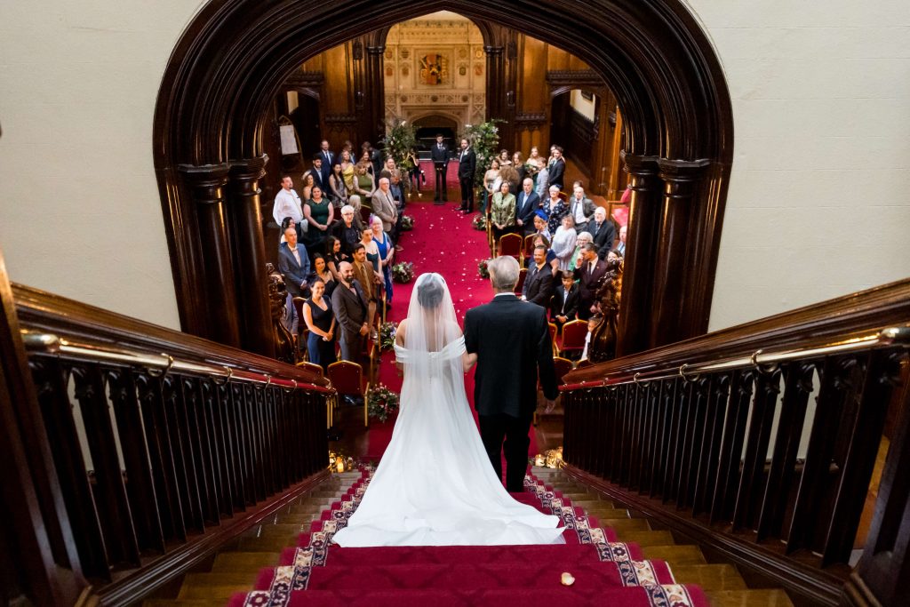 Bride and her father walking down the grand staircase at Allerton Castle