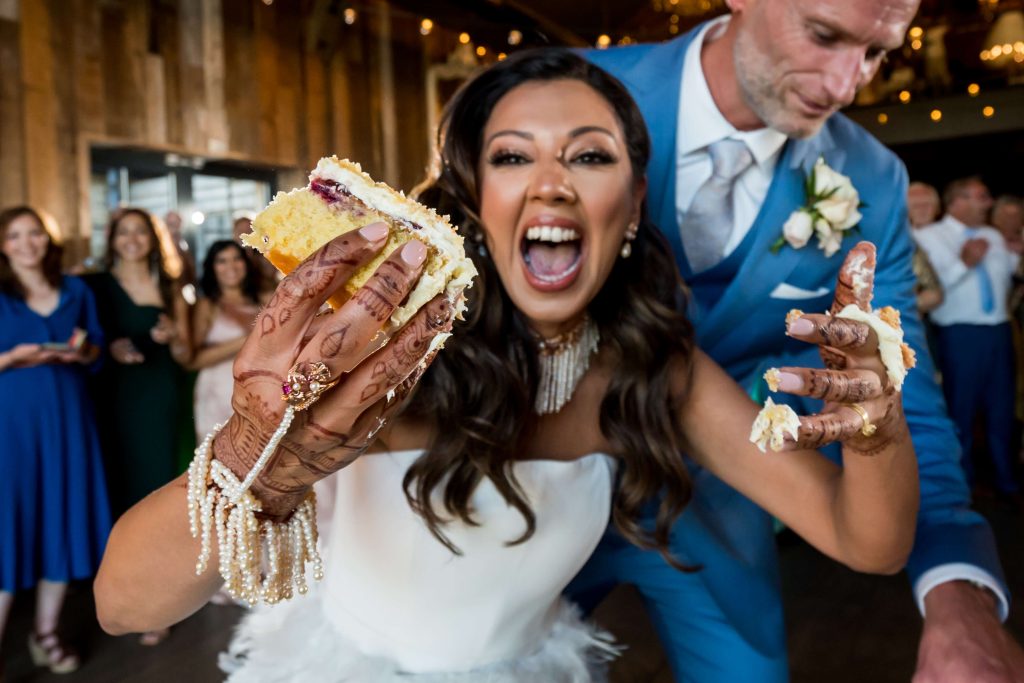 Joyful bride and groom with wedding cake on hands.