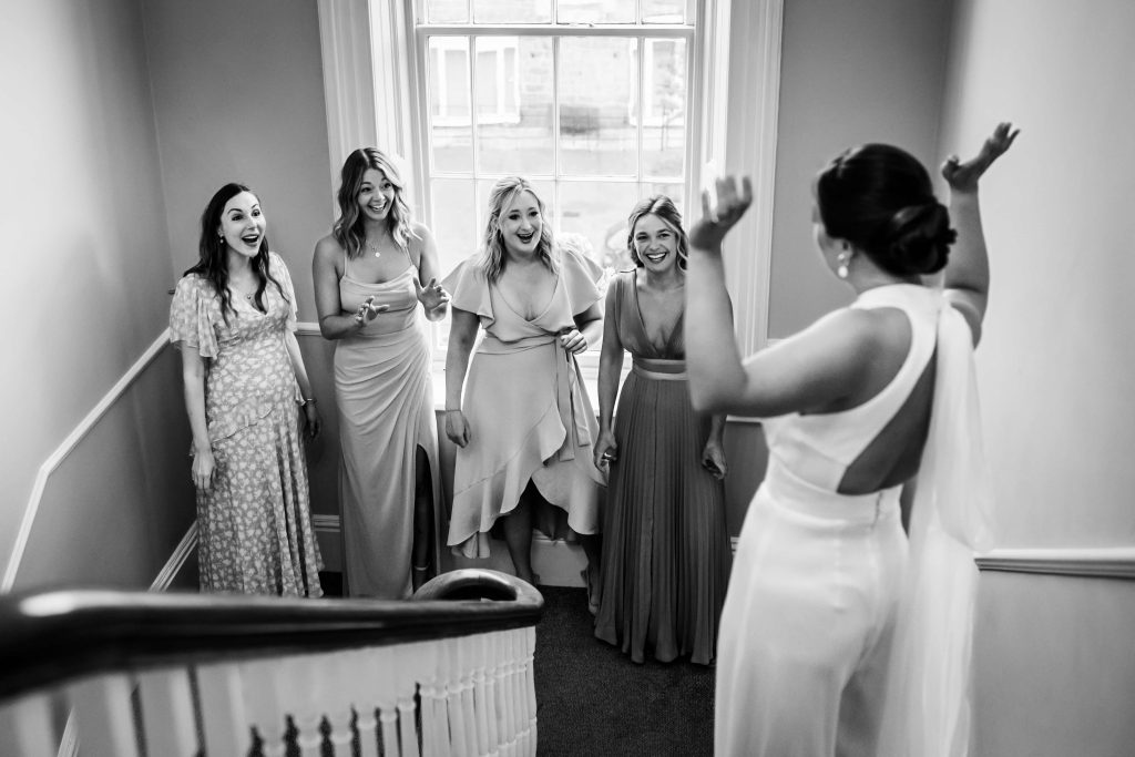 Bride and bridesmaids laughing together in black and white.