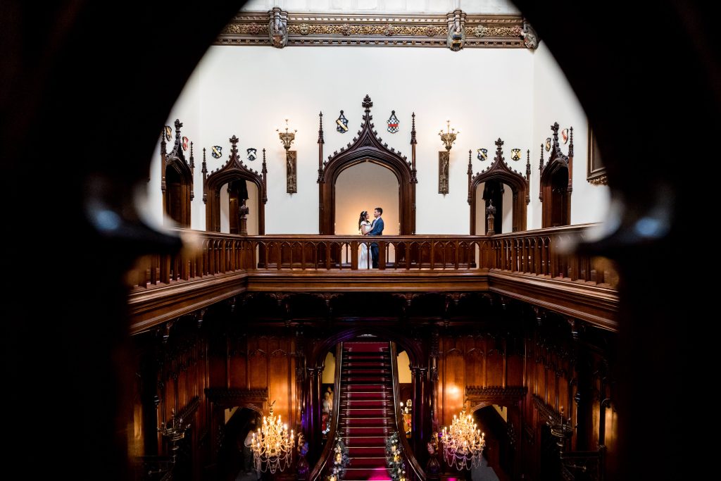 Couple embracing in grand, ornate balcony at Allerton Castle