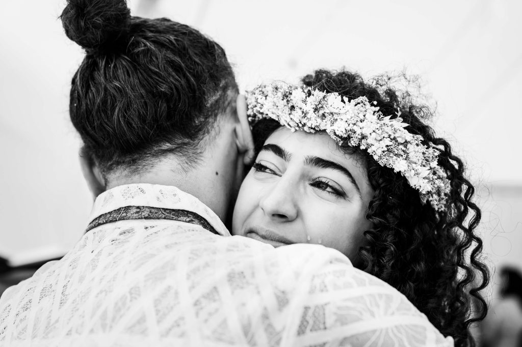 Couple embracing, woman with floral crown crying, black and white.