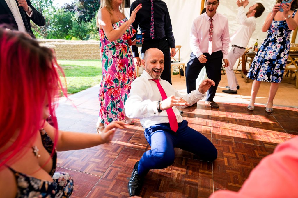 Man dancing enthusiastically at lively wedding reception.