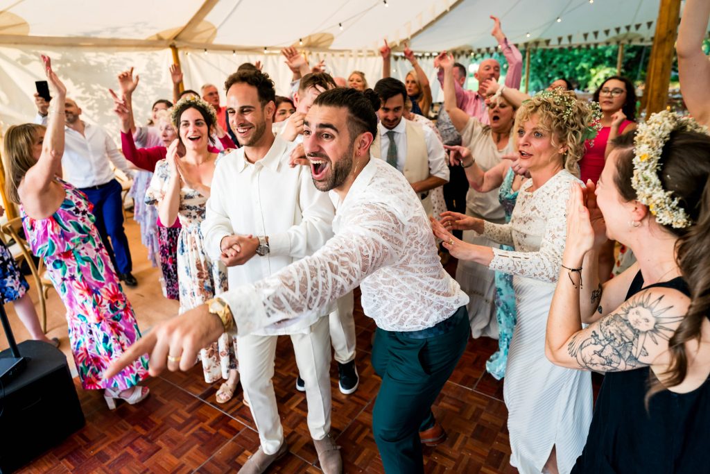 Joyful wedding guests dancing in a marquee.