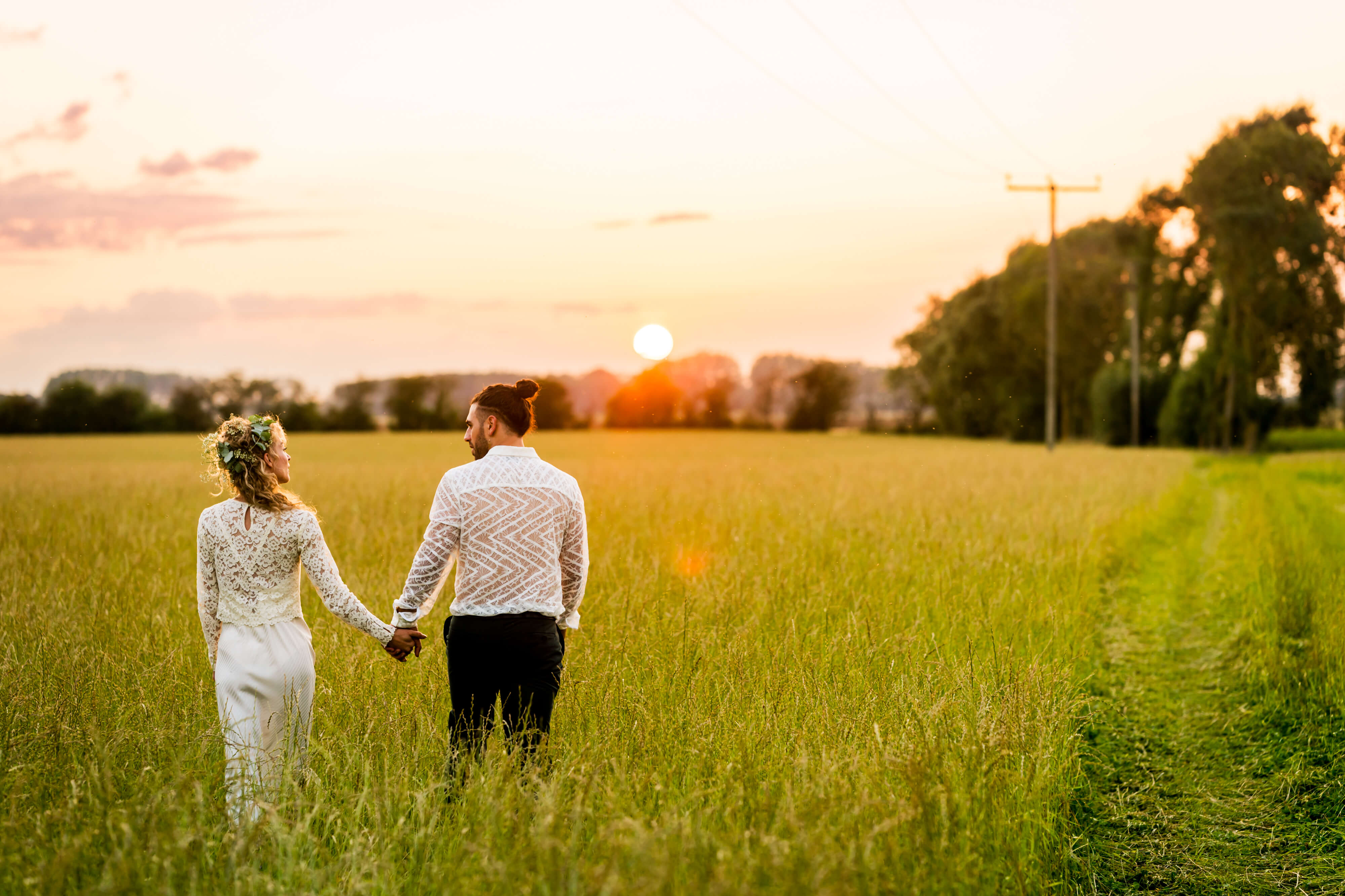 Couple holding hands in sunset field.
